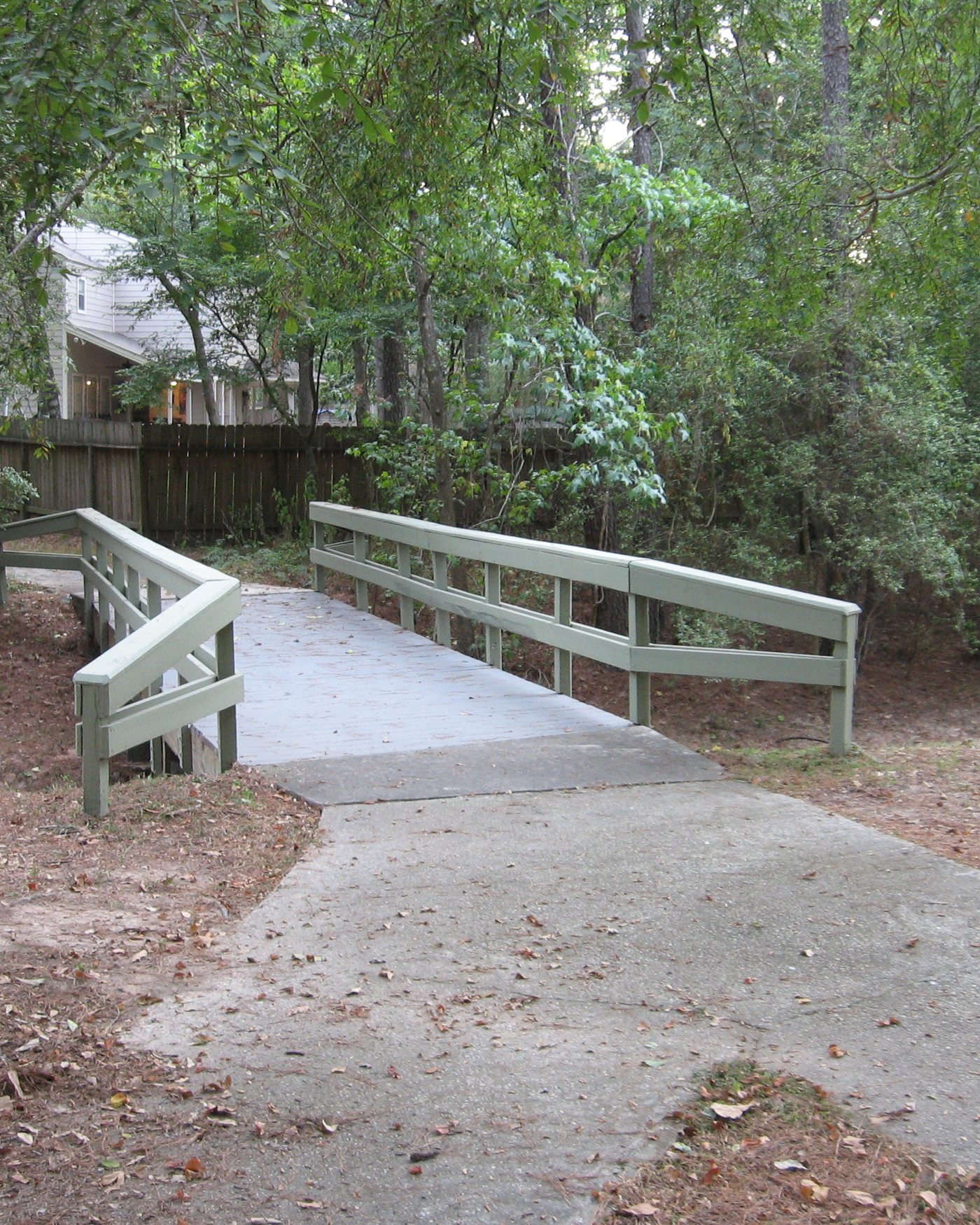 Paved greenbelt path and footbridge through trees in The Woodlands, Texas